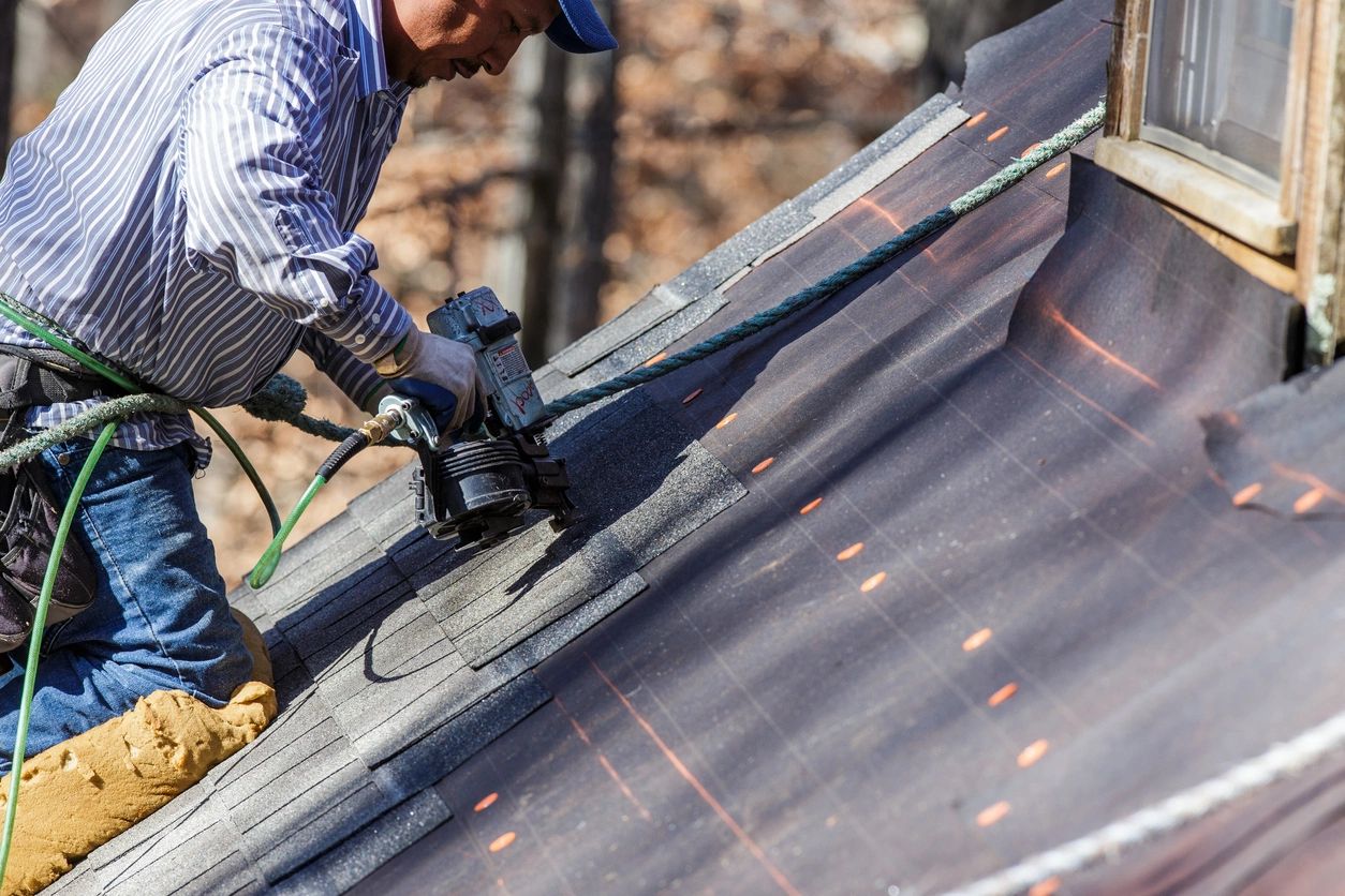 Worker using a power tool to cut a roofing material.
